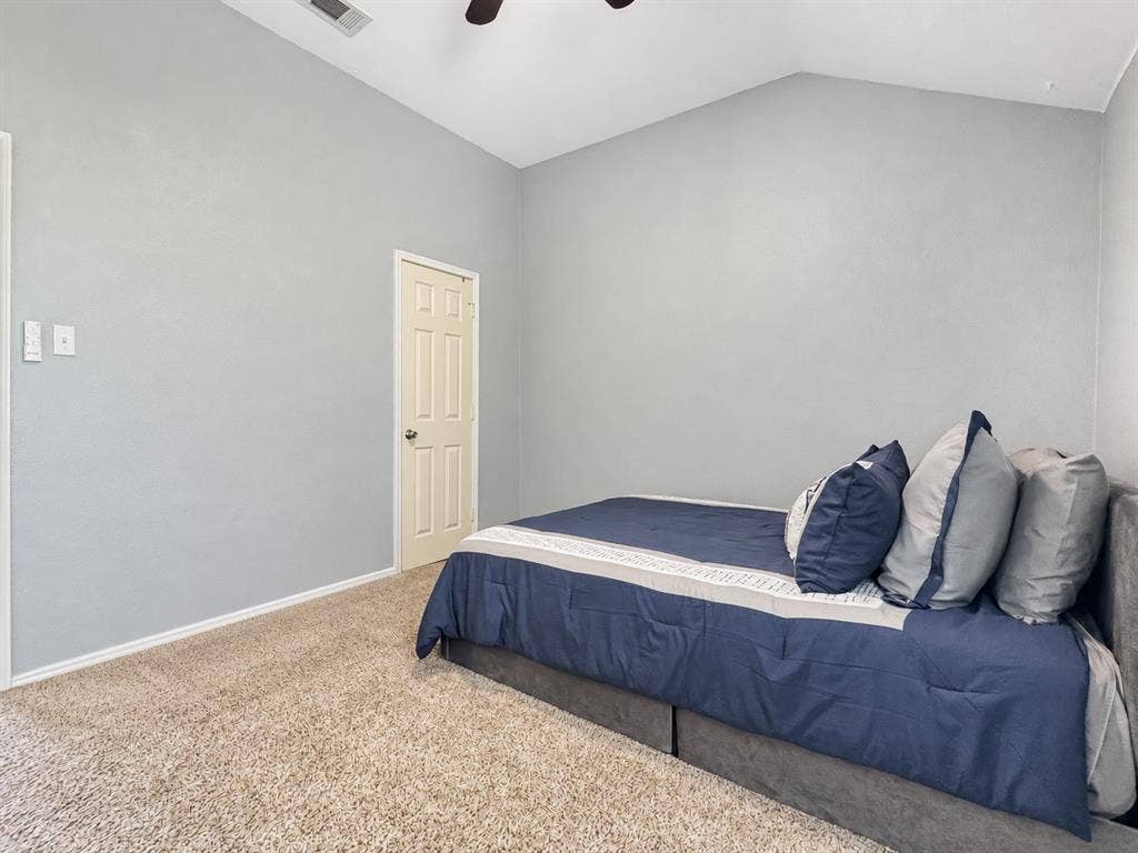 Vaulted ceilings featuring a mounted overhead fan, neutral wall paint, and interior six-panel door