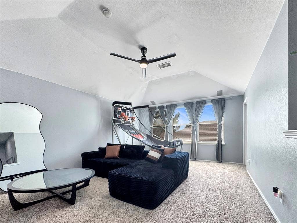Vaulted ceiling, neutral wall tones, multi-pane windows, and a matte black integrated ceiling fan