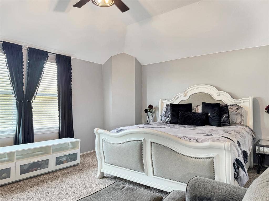 Vaulted ceiling, carpeted flooring, and a ceiling fan
