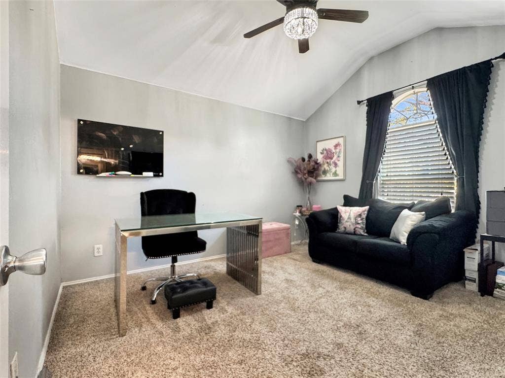Vaulted ceiling featuring an integrated ceiling fan with light fixture, neutral wall finishes, carpeted flooring, and an arched window