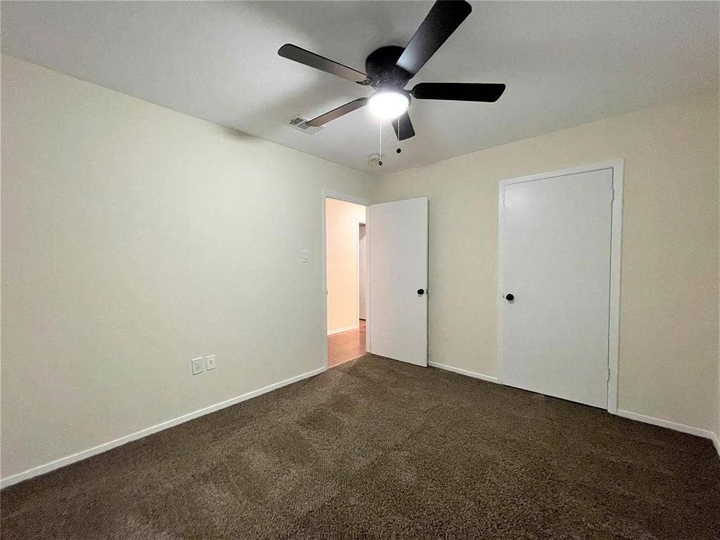 Room featuring neutral wall tones, carpeted flooring, and a ceiling fan with integrated lighting
