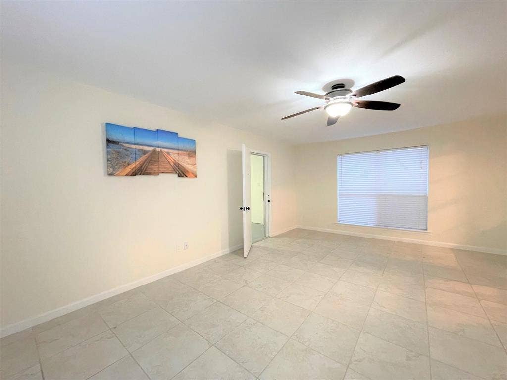 Neutral-toned ceramic tile flooring, ceiling fan with integrated light fixture, and single-pane window with horizontal blinds