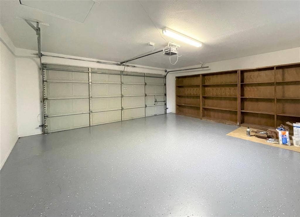Garage featuring an epoxy-coated floor, a sectional metal overhead door, and extensive built-in wood shelving