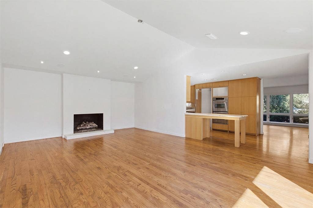 7606 Currin Drive, Dallas, TX 75230 Open living area featuring vaulted ceilings, wood-finish flooring, a recessed fireplace, recessed lighting, and built-in cabinetry with stainless steel wall ovens