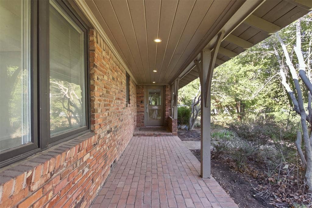 7606 Currin Drive, Dallas, TX 75230 Covered brick porch featuring recessed lighting, a brick floor, and wood-paneled ceiling