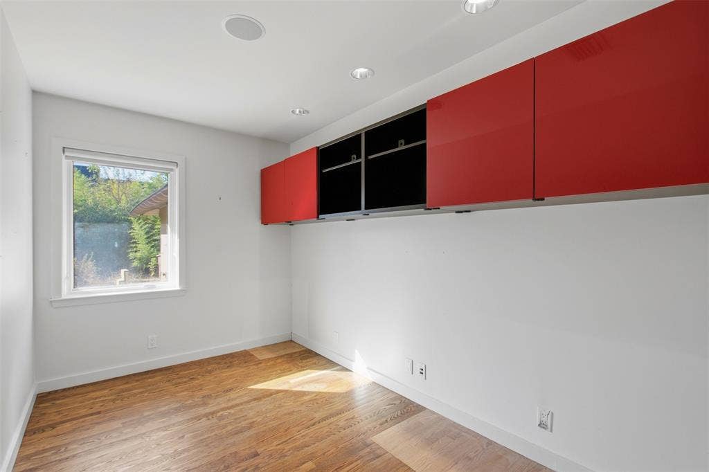 7606 Currin Drive, Dallas, TX 75230 Wood-finish flooring, recessed ceiling lighting, and wall-mounted red and black cabinetry with a high-gloss finish