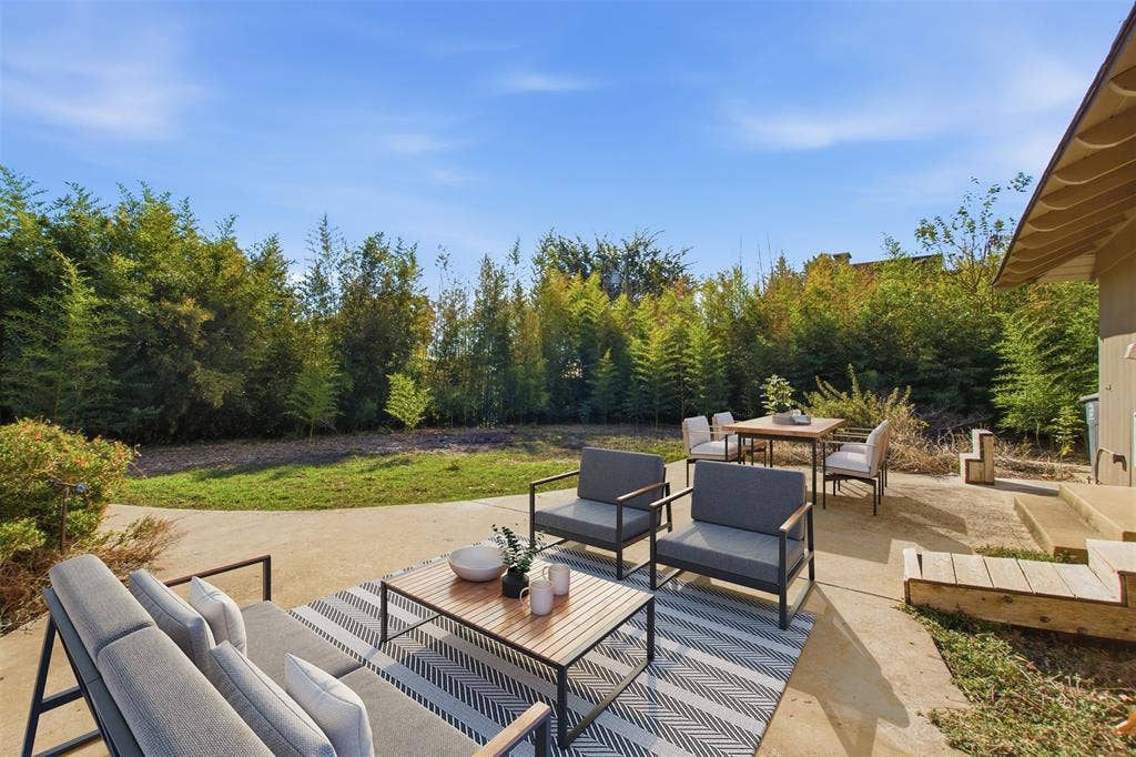 7606 Currin Drive, Dallas, TX 75230 Concrete patio with a grassy lawn, mature perimeter trees.