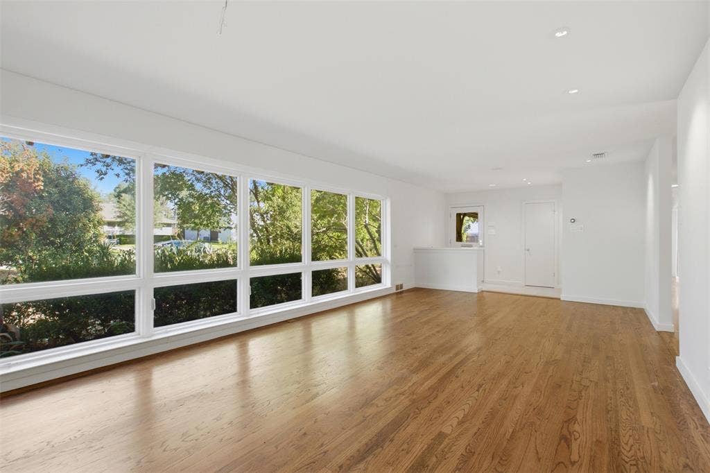 7606 Currin Drive, Dallas, TX 75230 Expansive living area featuring wood-finish flooring, extensive floor-to-ceiling windows, and recessed lighting