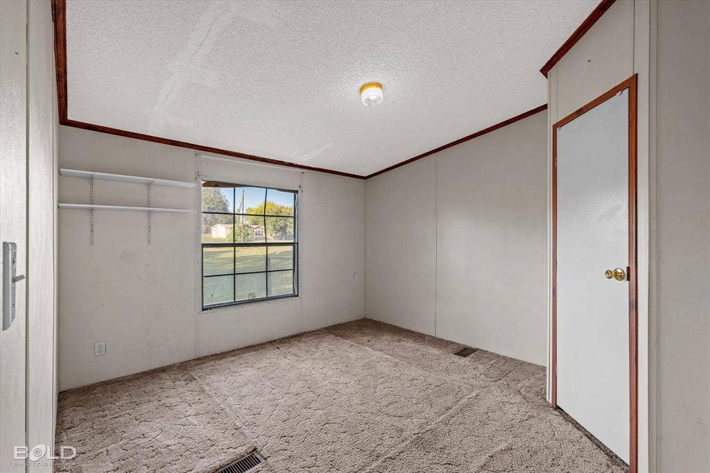 Interior room featuring neutral wall finishes, carpeting, a single-pane window with a grid pattern, built-in shelving, and a wood-trimmed interior door