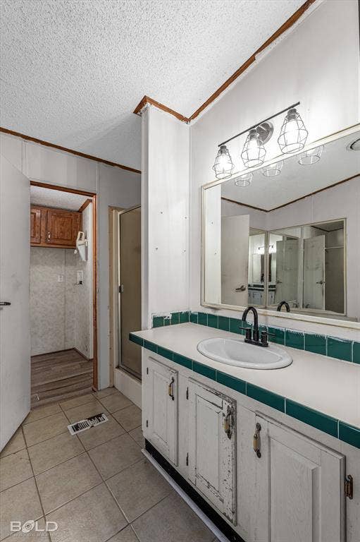 Bathroom vanity featuring a white cabinet base, tile countertop with a green tiled backsplash, integrated oval sink, and dark metal faucet, accompanied by a large wall-mounted mirror and a three-light fixture