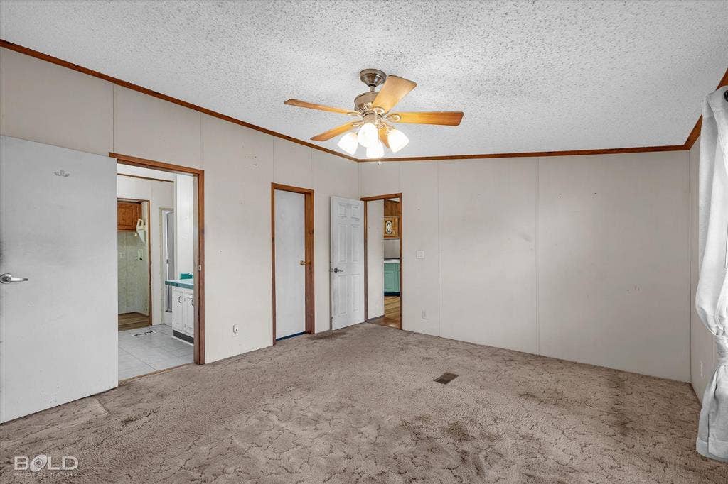 Interior space featuring carpeting, wood-trim detailing, and a multi-light ceiling fan