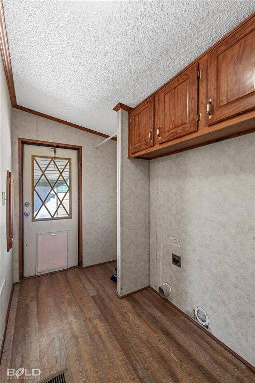 Utility space featuring wood-finish flooring, upper wooden cabinetry, and an exterior door with a diamond-patterned window pane