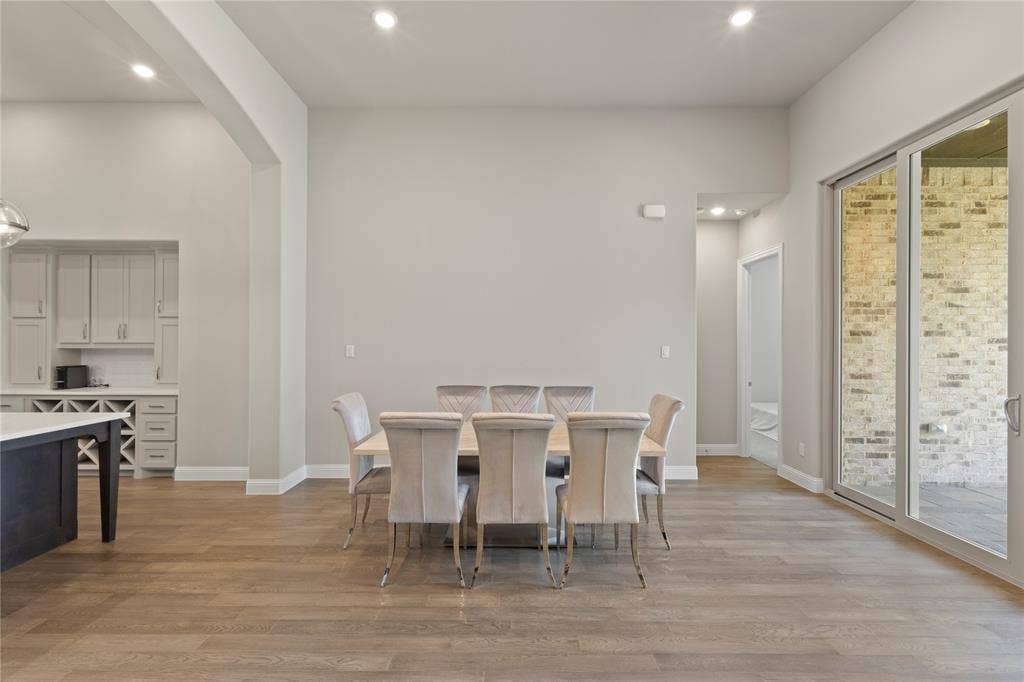 Open-concept area featuring wood-finish flooring, recessed lighting, expansive glass sliding doors, and built-in cabinetry with integrated wine storage