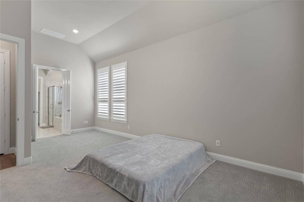 Vaulted ceilings, neutral carpeting, and windows fitted with plantation shutters