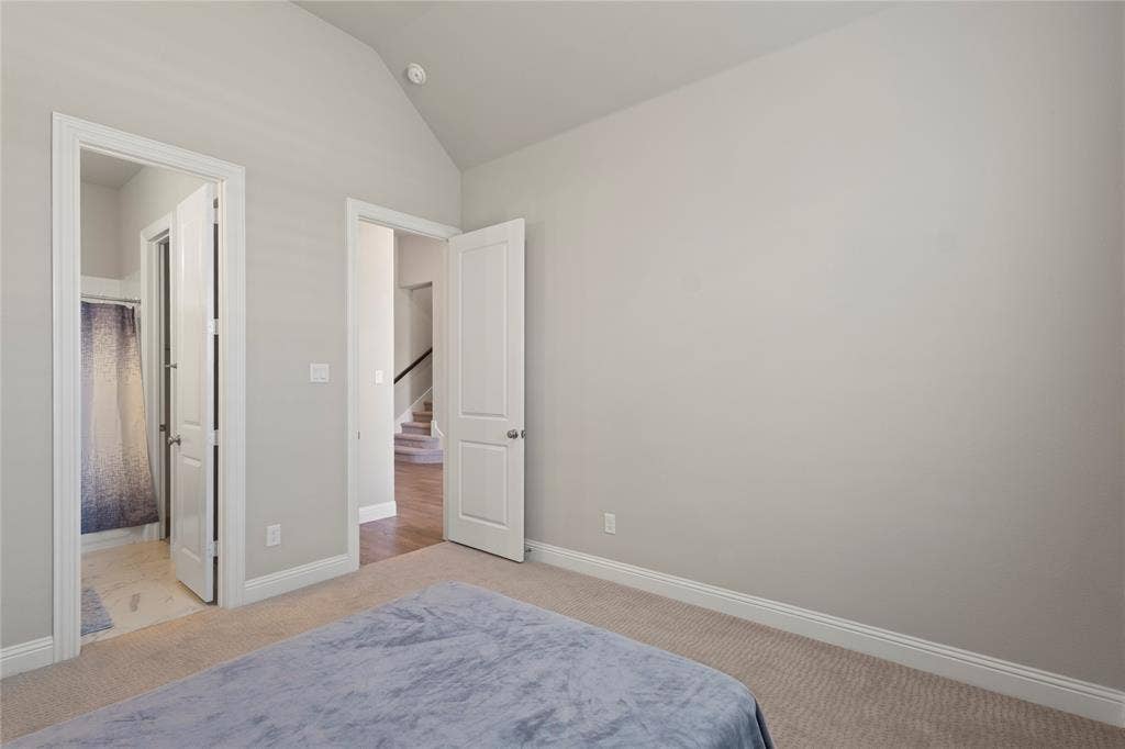 Interior room featuring vaulted ceilings, neutral wall paint, carpeted flooring, and two-panel interior doors