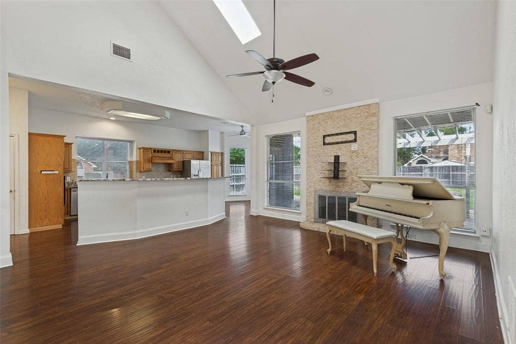 2306 Bent Brook Drive, Mesquite, TX 75181 Vaulted ceilings with an integrated skylight, wood-finish flooring, a stone-surround fireplace, and an expansive breakfast bar