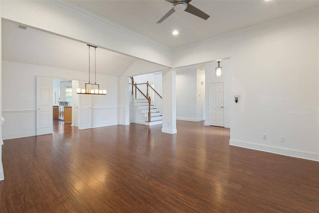 2306 Bent Brook Drive, Mesquite, TX 75181 Open interior space featuring wood-finish flooring, vaulted ceilings, crown molding, a multi-light pendant fixture, and a staircase with a wooden handrail