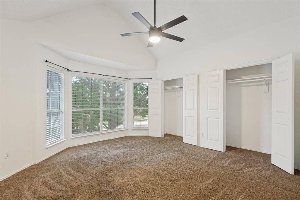 2306 Bent Brook Drive, Mesquite, TX 75181 Vaulted ceilings with a central matte black ceiling fan, expansive bay window, and dual closets featuring white paneled doors