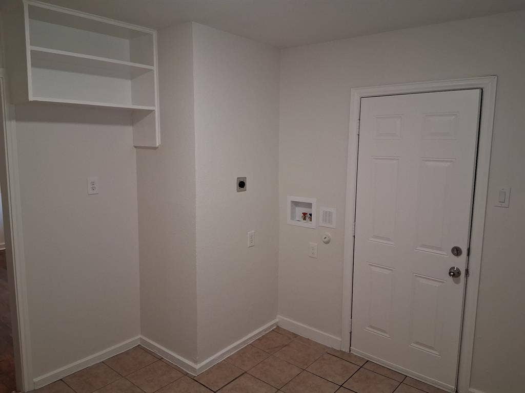 Utility area featuring ceramic tile flooring, built-in white overhead cabinetry, and recessed wall connections for appliances