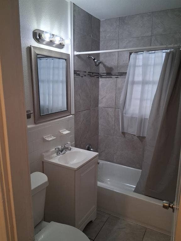 Bathroom featuring a vanity with an integrated sink, polished chrome faucet, rectangular wall mirror with a brushed-finish frame, and a tub-shower combination with floor-to-ceiling tile surround