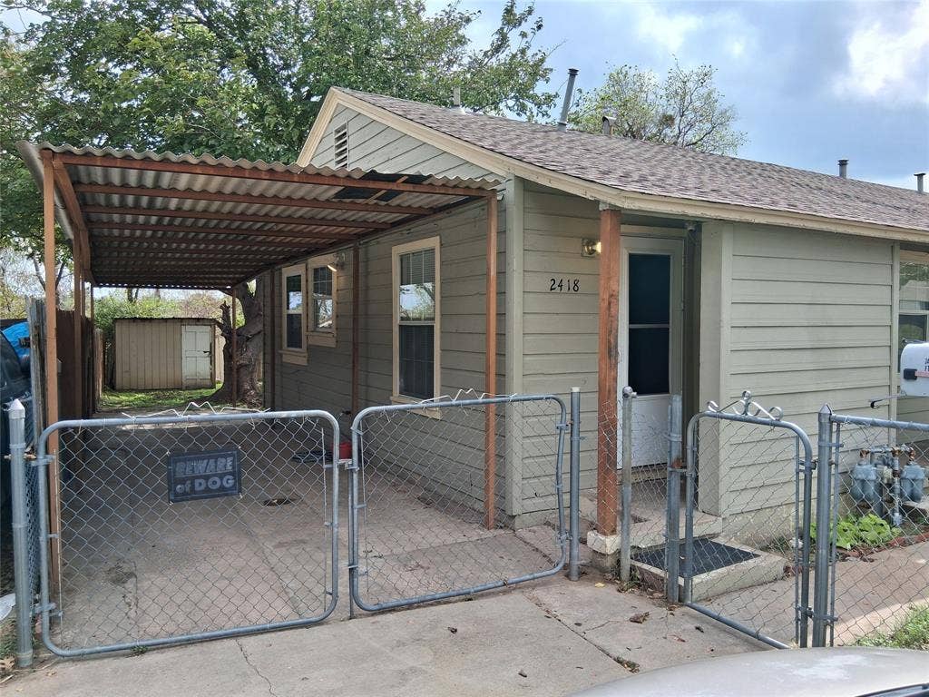 Single-story residence featuring horizontal lap siding, a metal-roofed carport, and fenced exterior grounds