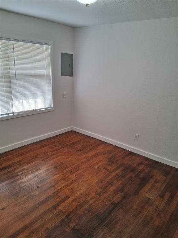 Wood-finish flooring, neutral wall tones, window with horizontal blinds, and a ceiling-mounted light fixture