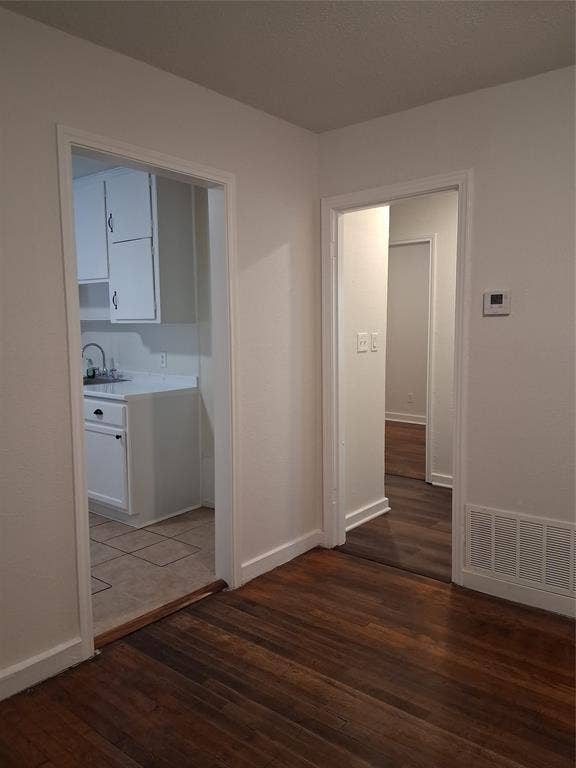 Interior space featuring wood-finish flooring, white cabinetry, and square-tile flooring in the culinary area