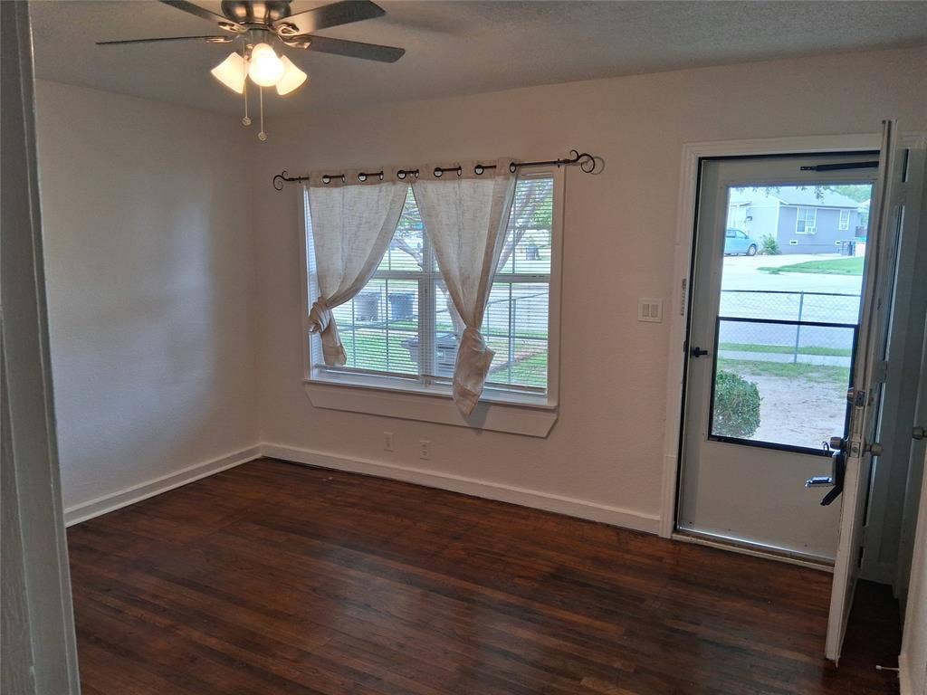 Wood-finish flooring, multi-pane window with custom rod, and ceiling fan with integrated lighting