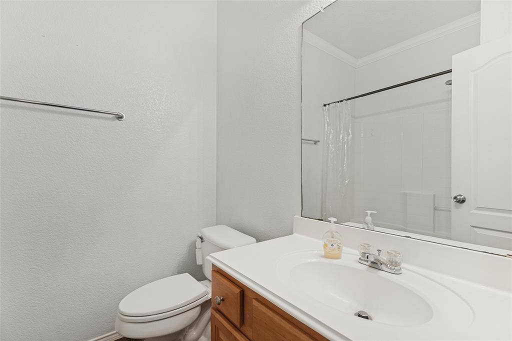 Bathroom featuring a wood-finish vanity with a white countertop and integrated sink, chrome faucet, large wall-mounted mirror, and a shower-tub combination with white surround