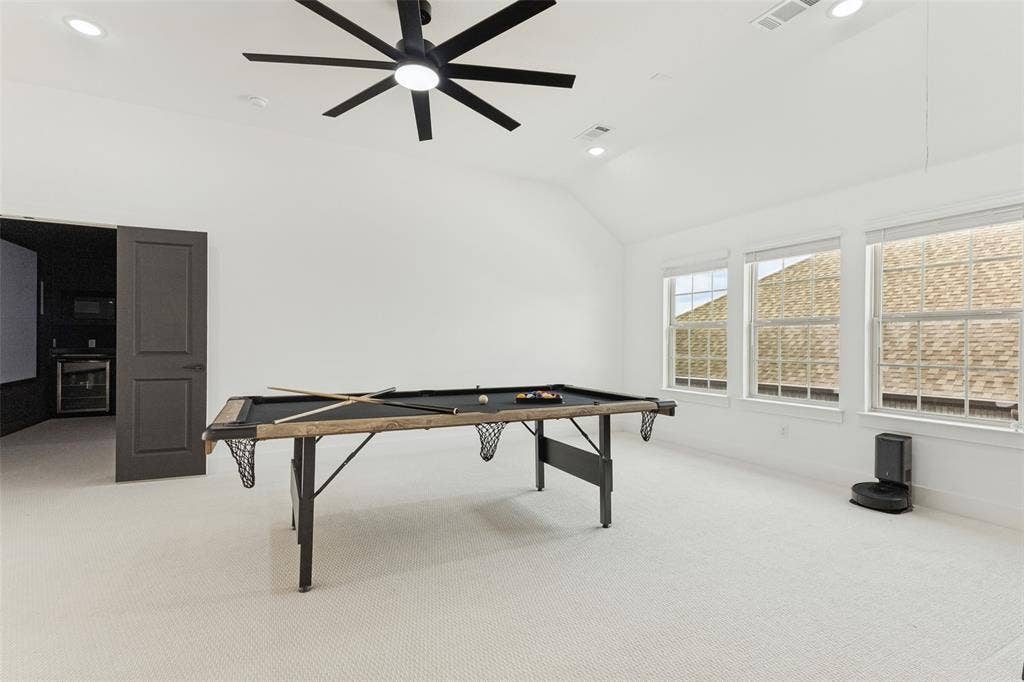 Vaulted ceiling featuring a multi-blade ceiling fan with integrated lighting, recessed lighting, neutral wall-to-wall carpeting, and triple-paned windows