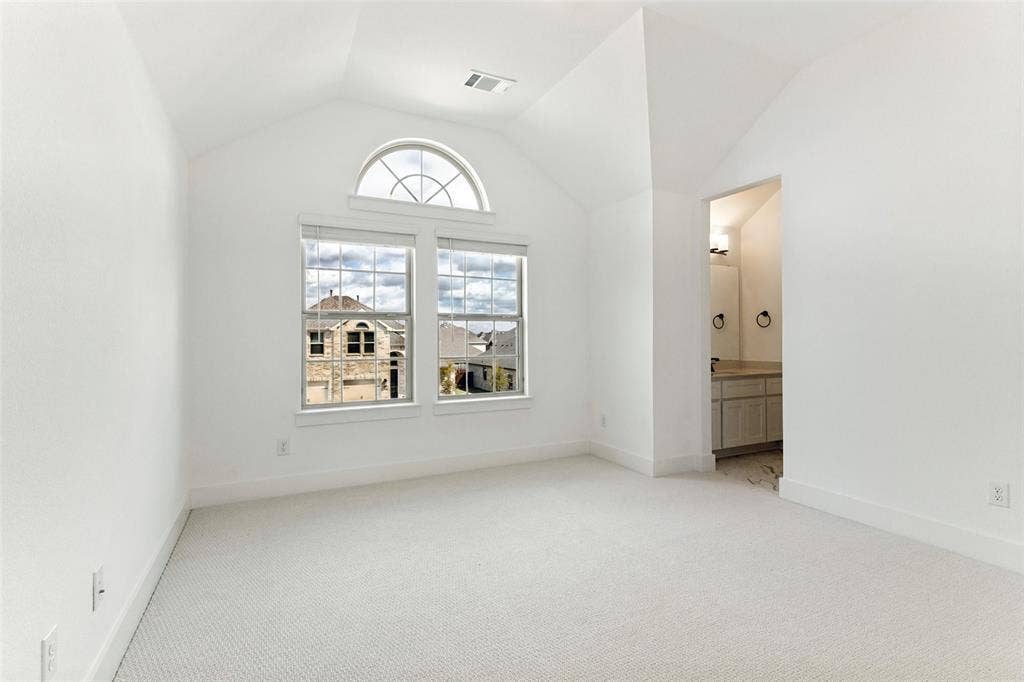 Vaulted ceilings, arched transom window, dual pane windows with integrated muntins, and neutral wall-to-wall carpeting