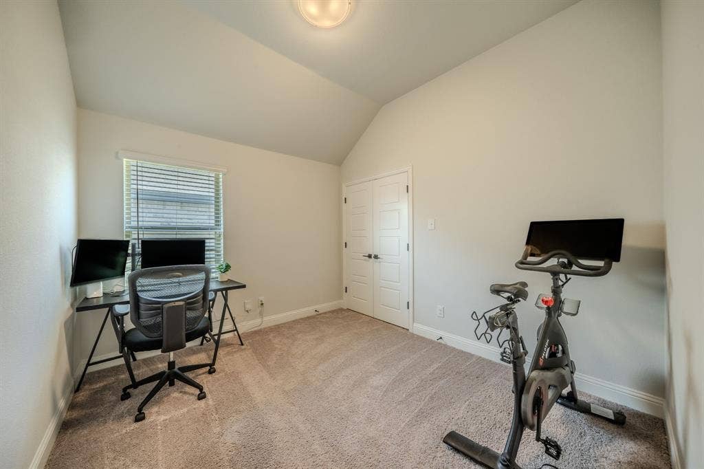 Vaulted ceilings, neutral carpeting, double-panel interior door, and a multi-pane window with adjustable blinds