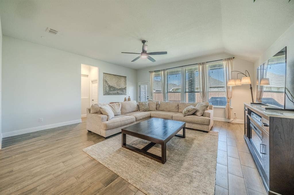 Living area featuring vaulted ceilings, wood-finish tile flooring, and oversized windows