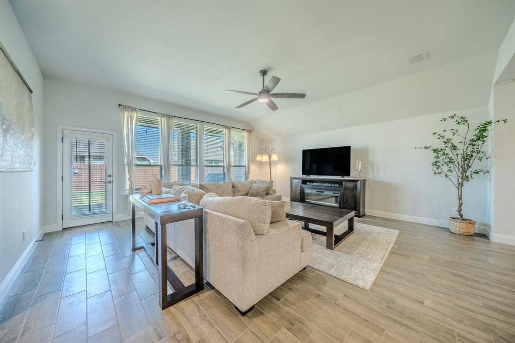 Vaulted ceilings, wood-finish tile flooring, recessed lighting, ceiling fan, and large windows