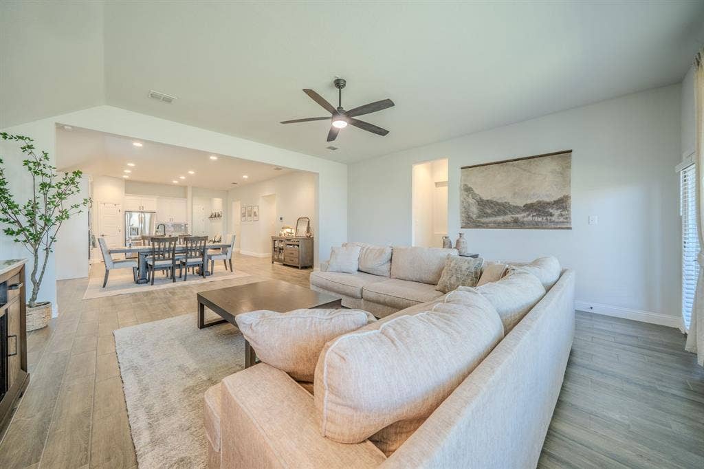 Vaulted ceilings, wood-finish flooring, recessed lighting, and a multi-blade ceiling fan