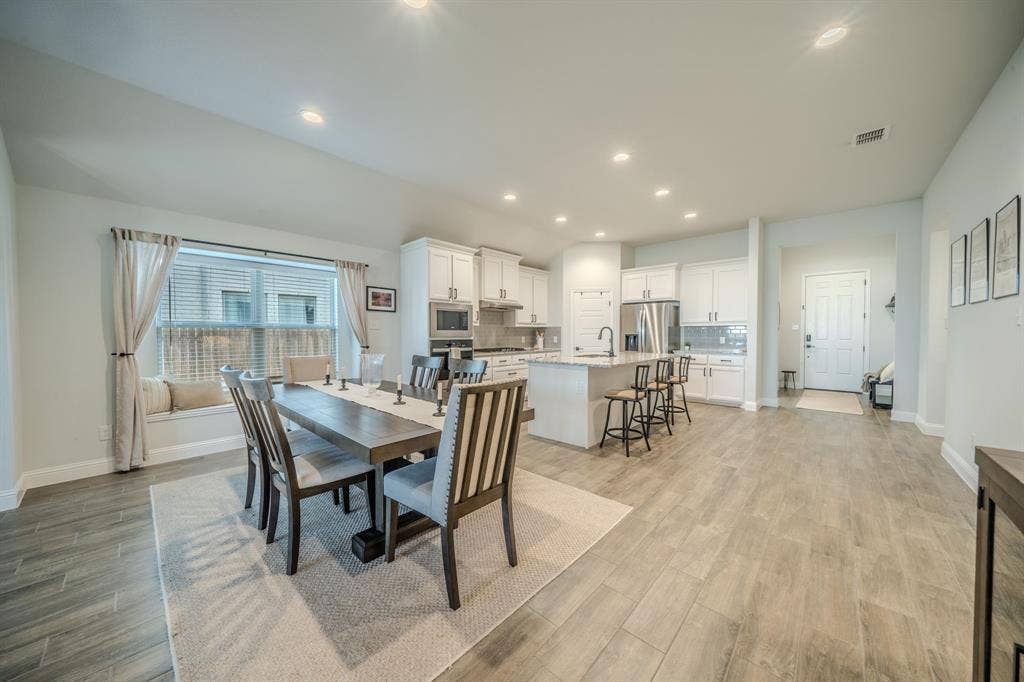 Kitchen featuring white shaker cabinetry, a center island with quartz countertops, recessed lighting, and wood-finish flooring throughout