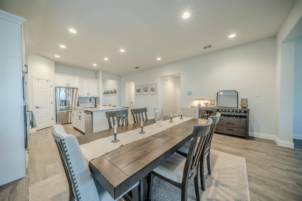 Kitchen featuring white cabinetry, stone countertops, stainless steel appliances, and wood-finish flooring throughout