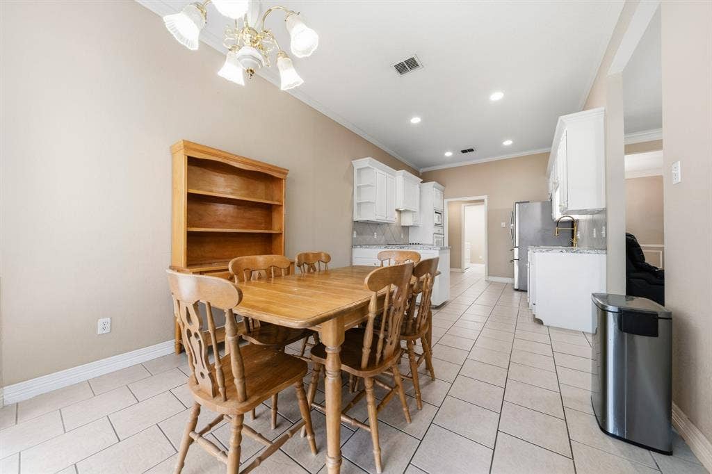 Kitchen and dining area featuring ceramic tile flooring, white cabinetry, recessed lighting, and a multi-arm chandelier