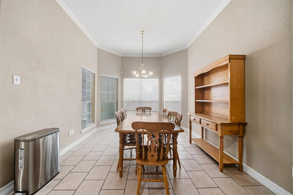 High ceilings with crown molding, ceramic tile flooring, bay windows with blinds, and a multi-arm chandelier