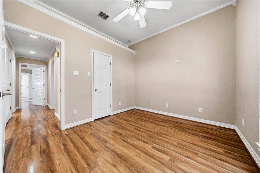 Room featuring wood-finish flooring, crown molding, and a ceiling fan with integrated light fixture
