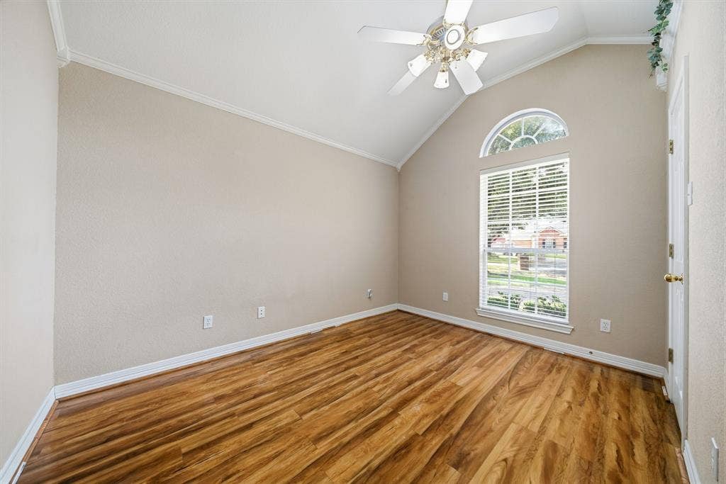 Vaulted ceiling featuring a ceiling fan, wood-finish flooring, and an arched window