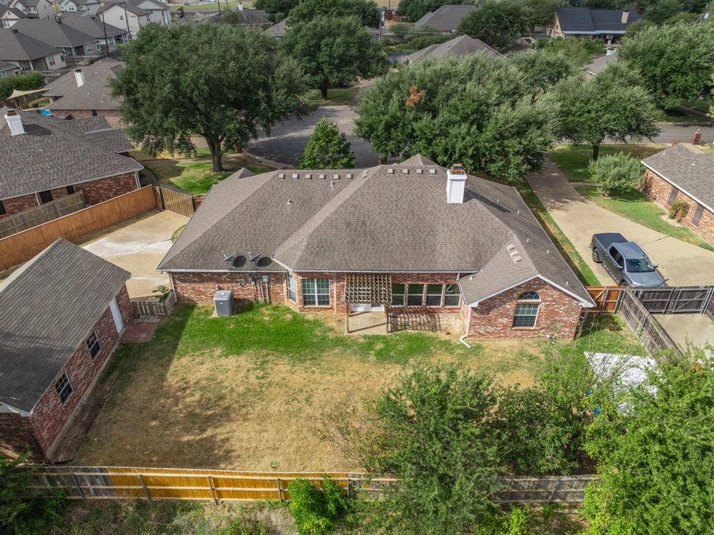Brick exterior, pitched asphalt shingle roof, integrated wooden pergola, and expansive fenced backyard