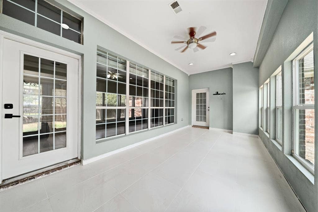 Sunroom/den featuring light-toned tile flooring, large multi-pane windows, transoms, and an integrated ceiling fan