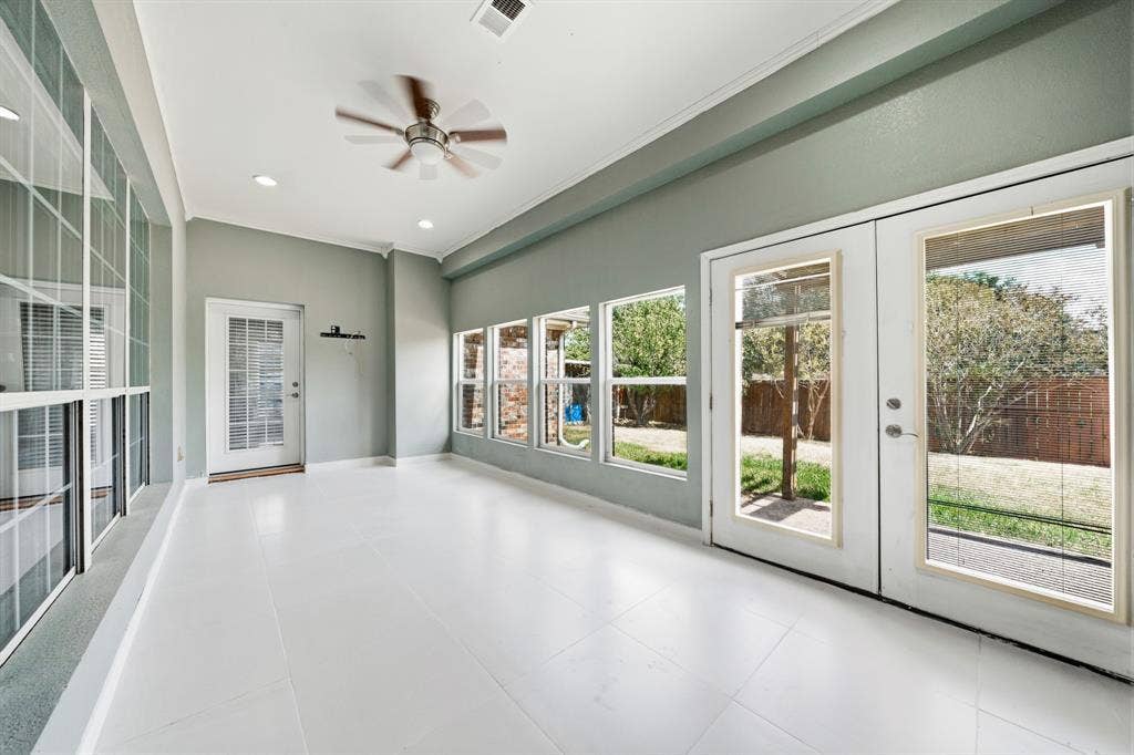 Sunroom/den featuring large windows, white tile flooring, ceiling fan with light fixture, and double glass-panel entry doors