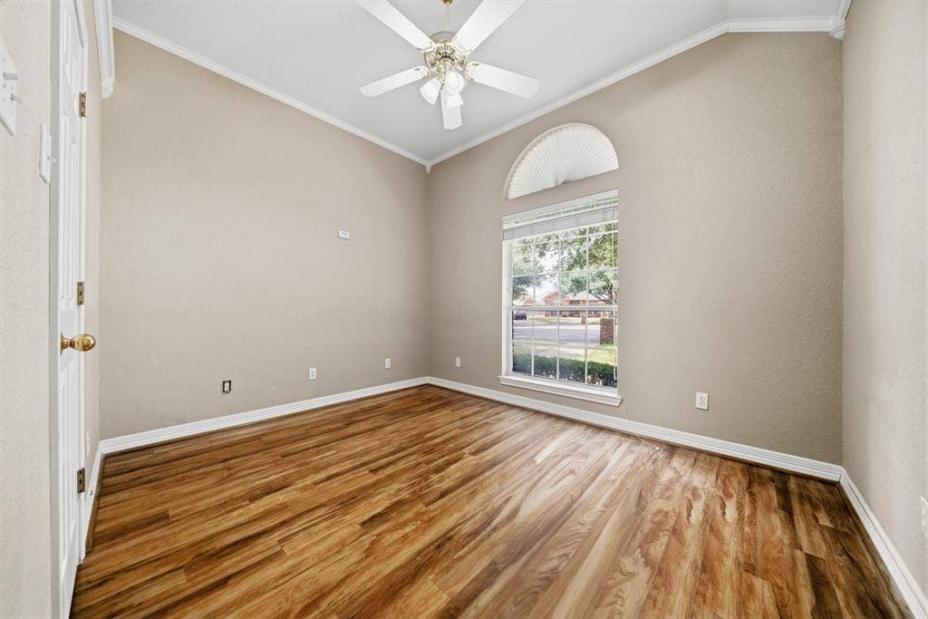 Vaulted ceiling with an integrated multi-blade ceiling fan, wood-finish flooring, and a large window featuring an arched transom top