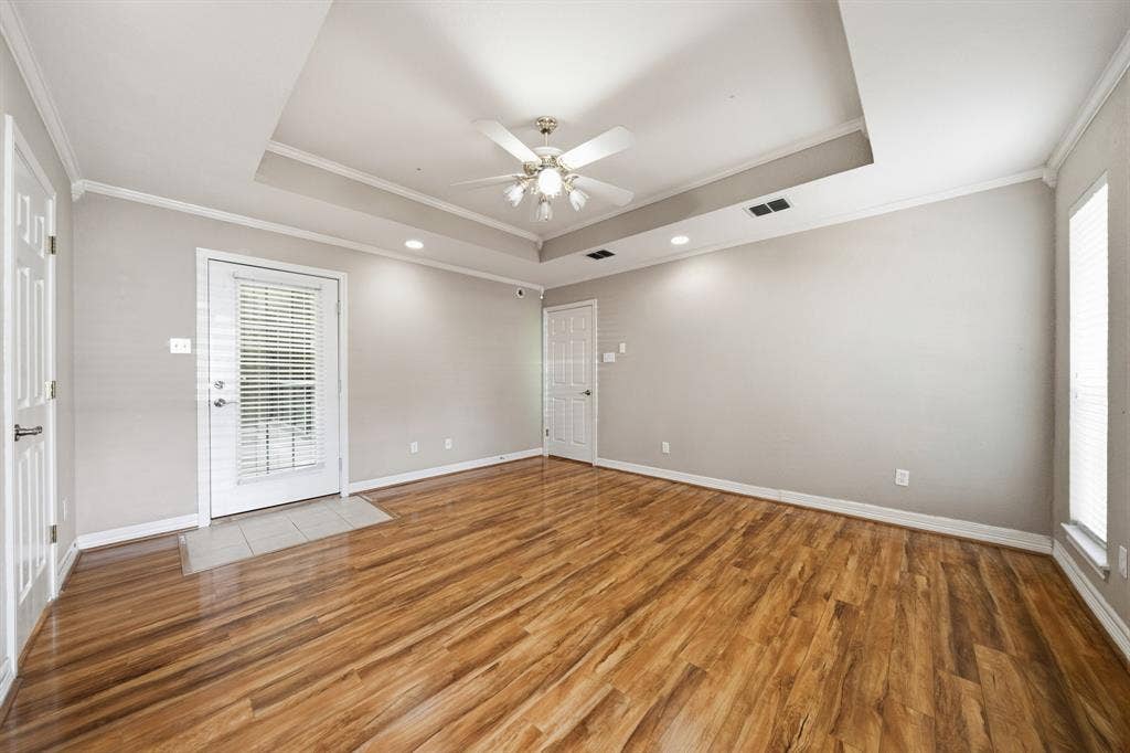 Tray ceiling featuring recessed lighting, wood-finish flooring, and a central ceiling fan with integrated light fixture