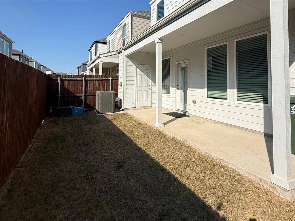 Covered concrete patio with horizontal lap siding, exterior entry door, and wood-panel privacy fencing