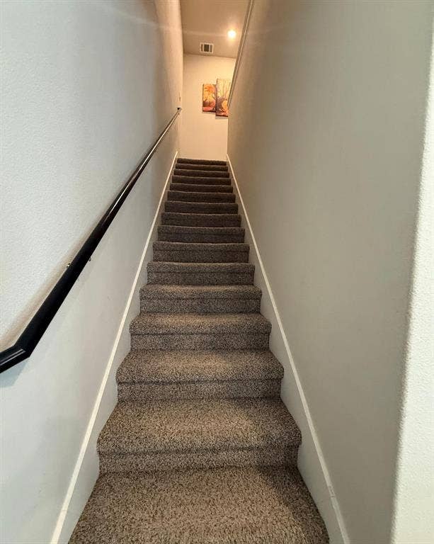 Staircase featuring wall-to-wall carpeting and a matte black handrail