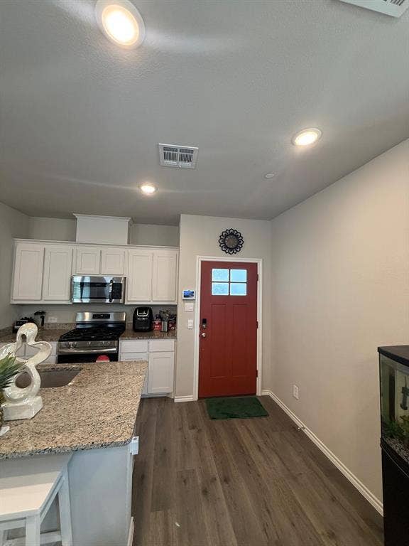 Kitchen featuring white cabinetry, stone-finish countertops, stainless steel gas range, recessed lighting, and wood-finish flooring
