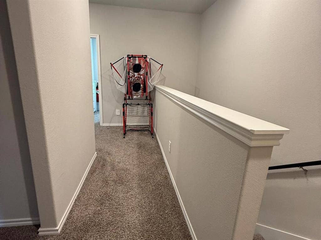 Neutral-toned interior space featuring carpeted flooring and a partial-height wall with decorative trim detailing